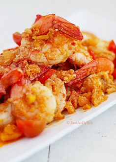 a white plate topped with cooked shrimp and tomatoes