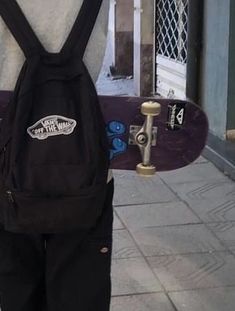 a skateboarder is standing on the sidewalk with his back pack attached to his backpack