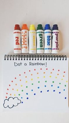 a notepad with markers and crayons on it that says dot a rainbow