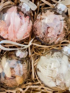 four glass ornaments in a basket with ribbon and tags on the top one is filled with feathers