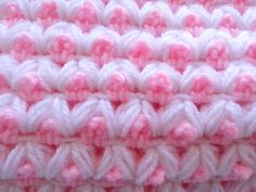 a close up view of a pink and white crocheted blanket