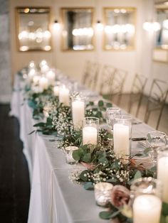 a long table with candles and greenery on it is set up for an event