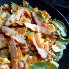 a salad with chicken, lettuce and carrots on it is sitting on a black plate