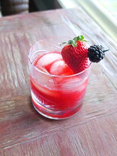 a glass filled with ice and fruit on top of a wooden table