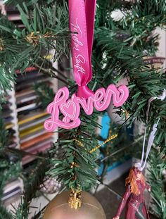 a pink ornament hanging from the top of a christmas tree next to other ornaments