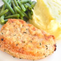 a white plate topped with meat, mashed potatoes and veggies next to green beans