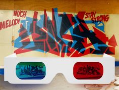 two 3d glasses with graffiti on them sitting in front of a wall