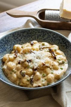 a bowl filled with macaroni and cheese on top of a table next to a slice of bread