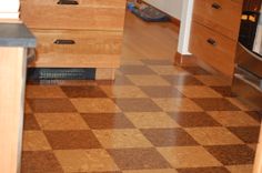 the kitchen floor is covered in brown and white checkerboard tiles, with drawers on each side