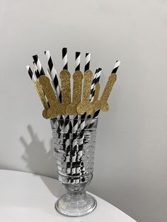 black and white striped straws with gold glitter hand prints in a clear glass vase