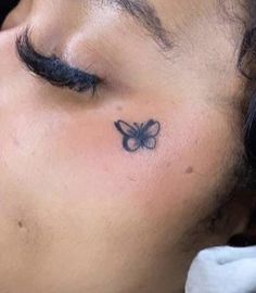 a close up of a person with a butterfly tattoo on their forehead and behind his ear