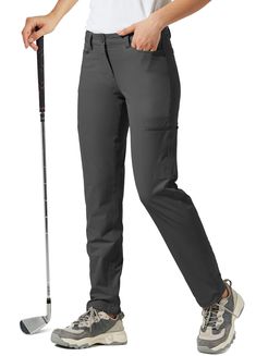 a woman in grey pants holding a golf club