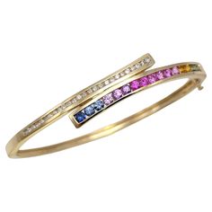 Shown here is an absolutely gorgeous bypass bracelet bursting with color and sparkle. Crafted with the utmost artistry, this incredible piece is adorned with a captivating combination of natural sapphires and diamonds, set in the luxurious 14 karat yellow gold. A stunning statement piece that will truly light up your wrist! The centerpiece of this remarkable hinged bracelet is the array of natural sapphires, boasting a total carat weight of 2.03. The sapphires feature a round cut, carefully face Rainbow Sapphires, Round Sapphire, Sapphire Color, Hinged Bracelet, Channel Set, Natural Sapphire, Sapphire Diamond, Diamond Clarity, Bangle Bracelet