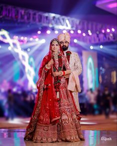 a bride and groom pose for a photo in front of the stage at their wedding reception