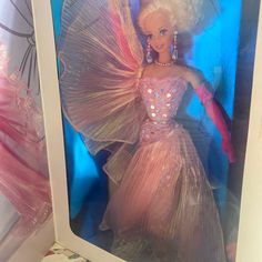 a barbie doll in a pink dress and tiara is standing next to a mirror