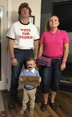 a man and woman standing next to a little boy holding a sign