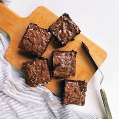 chocolate brownies on a cutting board next to a knife and fork, ready to be eaten