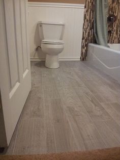 a white toilet sitting inside of a bathroom next to a bathtub and shower curtain