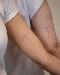 two people with cross tattoos on their arms