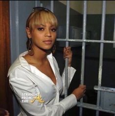 a woman standing behind bars in a jail cell with her hand on top of the bars