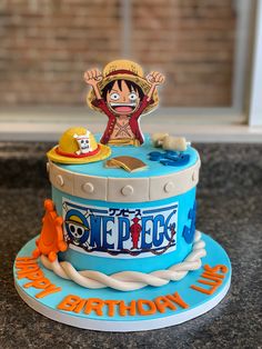 a birthday cake with an image of one piece on top and other items around it