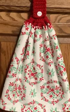 a red and white dress hanging on a wooden door with a crocheted button