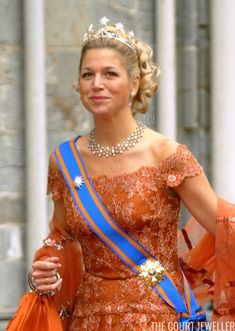 a woman in an orange dress with a tiara and blue ribbon around her neck