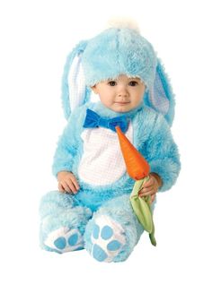 a baby in a blue bunny costume holding a carrot