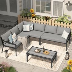 an outdoor living room with grey furniture and sunflowers