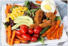 a white plate topped with chicken, veggies and sweet potato fries next to an egg