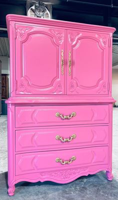 a pink armoire with gold handles in a room