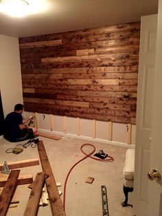 a man sitting on the floor in front of a wall made out of wood planks