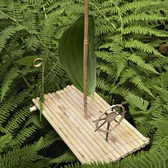 a small sailboat made out of wood and bamboo is sitting in the middle of ferns