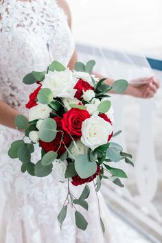 the bride is holding her red and white bouquet