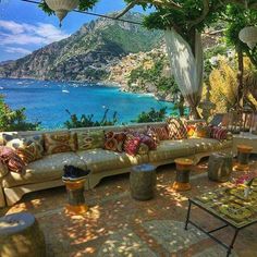 an outdoor seating area with lots of pillows on the couches and tables in front of it