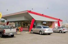 several cars are parked in front of a fast food restaurant that is red and white