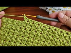 someone is crocheting the stitchs on a green piece of yarn with a needle