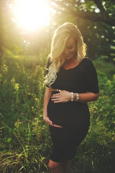 a pregnant woman is standing in the grass