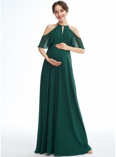 a pregnant woman in a green gown posing for the camera with her hand on her belly