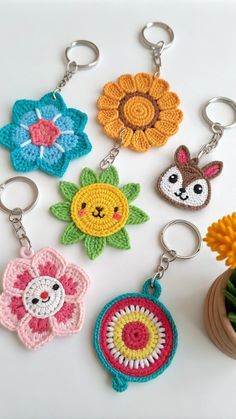 four crocheted keychains with flowers and animals on them, all in different colors