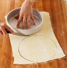 a person using a knife to cut dough into small circles on top of a wooden table