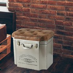 an old suitcase is sitting on the floor in front of a brick wall and window