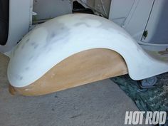 a white and wood bench sitting on top of a cement floor