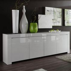 a white sideboard with two vases on top and one green vase in the middle