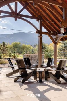 an outdoor dining table and chairs under a covered patio area with mountains in the background