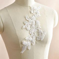 the back of a mannequin wearing a white dress with an embroidered design on it