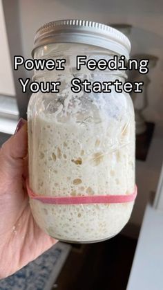 a person holding a jar with food in it and the words power feeding your starter