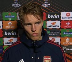 a man standing in front of a wall wearing a blue jacket