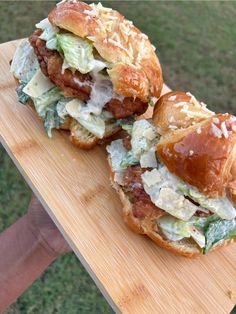 two sandwiches are sitting on a wooden board