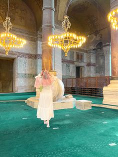 a woman in a white dress standing next to a large light fixture and chandelier